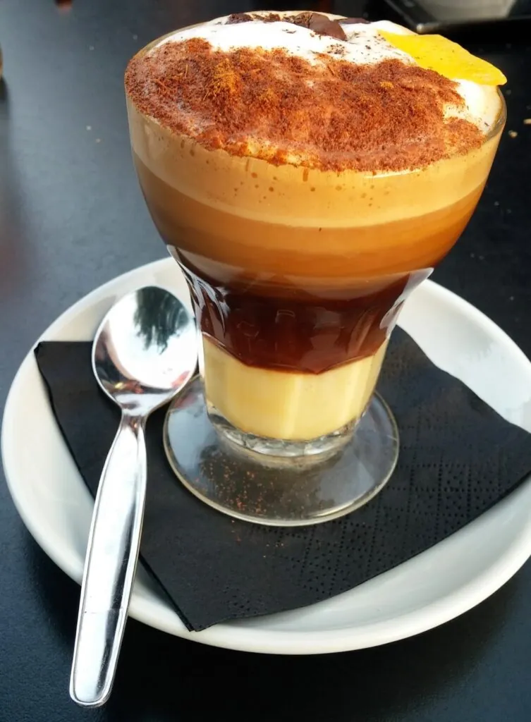 A cafe asiatico in its signature glass showing layers of condensed milk, liqueur and coffee