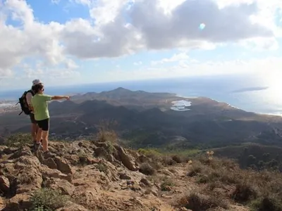 Senderistas señalando la costa de Calblanque desde un mirador de la sierra